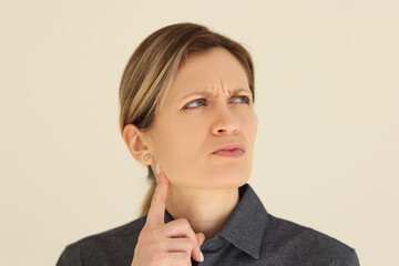 Pensive woman touches chin with finger looking to side