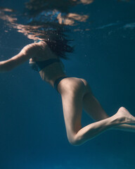 Fototapeta na wymiar young girl in swimsuit swims underwater