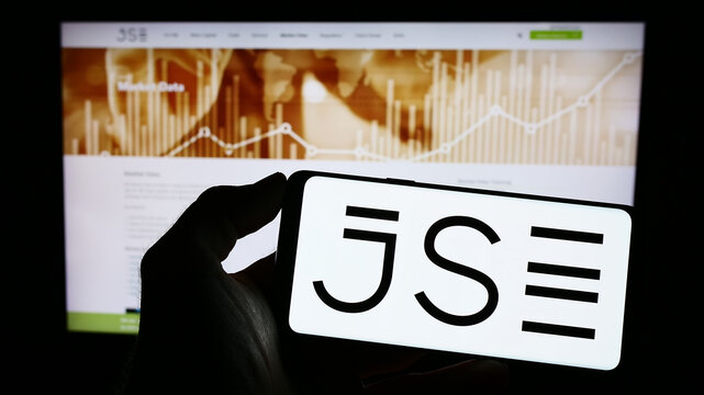 Stuttgart, Germany - 03-25-2023: Person holding cellphone with logo of JSE Limited (Johannesburg Stock Exchange) on screen in front of business webpage. Focus on phone display.