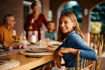 Happy teenage girl during family gathering on patio looking at camera.