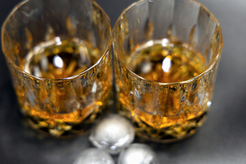 Two glasses of whiskey on a black background.