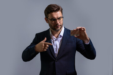 Credit card concept. Caucasian millennial successful 40s business man holding banking card isolated on gray background, studio portrait. People lifestyle concept. Purchasing and cashback rewards.
