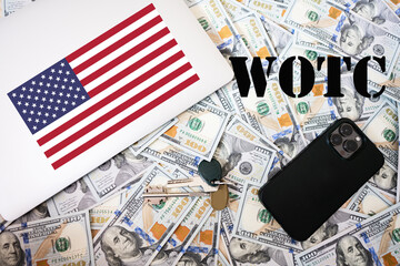 Fototapeta na wymiar WOTC. Work opportunity tax credit concept. USA flag, dollar money with keys, laptop and phone background.