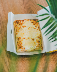 Un French tacos gratiné à la raclette dans sa boite à emporte,r prêt à petre consommé