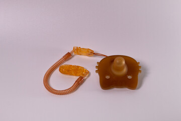 A baby pacifier with a orange plastic cover and a small orange pacifier. isolated on white...