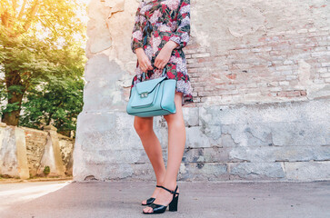 Slender legs of a woman. Holding an elegant women handbag