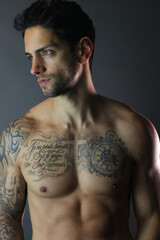 Fototapeta premium Handsome man with tattooes posing shirtless on gray background
