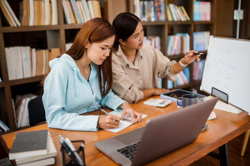 Asian student girl High School Tutor Individual Tuition From Teacher In Library. University Student Tutor books with friends.