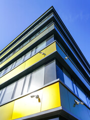 Fototapeta na wymiar Corner of the modern office house with surveillance cameras on blue sky background