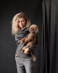 happy girl with a dog in a photo studio on gray.Red Poodle and curly woman