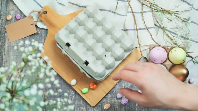 The hand opens the cardboard packaging of quail eggs. The concept of preparing for the Easter holiday with label mock up. Top view. 