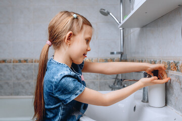 Getting rid of germs. The girl does morning water procedures for washing her hands by getting soap...