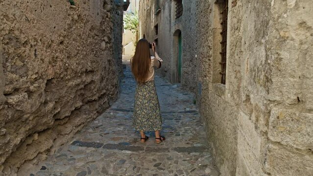 Young woman visiting an old town in Gerace, Italy. A female tourist taking pictures and exploring an old historical town in Italy. 