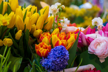 Close-up view of various multi-colored flowers (roses, tulips and hyacinths) on showcase of florist shop. Soft focus. Flower business theme.