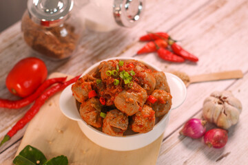 Selective focus of Bakso Mercon (spicy meatballs) on wooden spoon. traditional food from Java, Indonesia, cooked with various herbs.