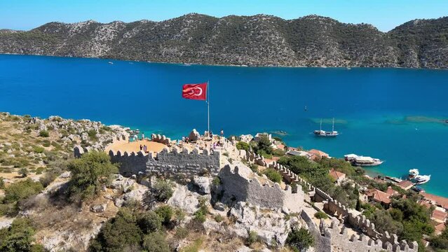 Drone video featuring Simena Castle (Kalek&ouml;y), beach, and yachts, providing a captivating view of the historical landmark and Mediterranean landscape in Antalya, Turkey.