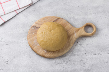 Wooden board with ready dough for koulourakya greek easter cookies with sesame seeds on gray textured background. Step by step instruction. Do it yourself. Step 5. Knead soft dough.