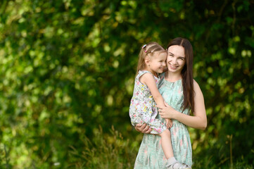 Portraits of joyful mother and daughter hugging, spend time together, enjoy happy family time. The concept of a happy family, family day, mother's day, countryside vacation, unity with nature.