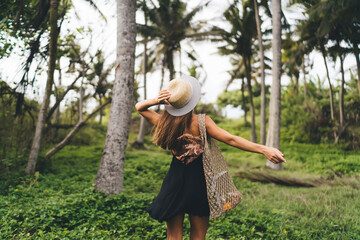 Unrecognizable woman walking in forest with handbag