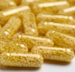 Transparent medical capsules with yellow granules inside on a white background, tablets for...