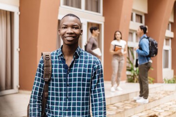 Black student smiling confidently holding books on the campus university.