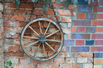 Obraz premium old stone brick wall with an old wooden wheel hanging on wall