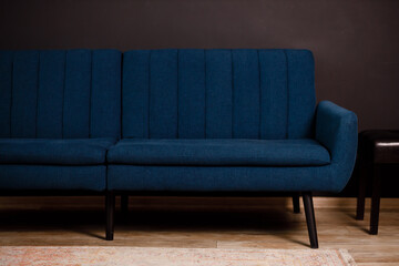 Blue stylish sofa in the living room. Designer interior. Dark tones of renovation in 2023