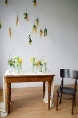Wooden table with fresh flowers in vases. The chair is near at home. Old style