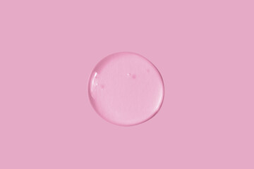 Large round drop of transparent cosmetic gel on a pink background