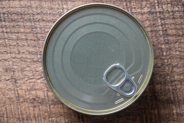 Closed canned food on a wooden background, closeup, top view