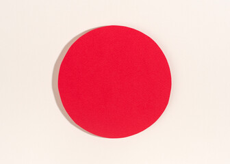 Red paper circle with shadow on white background.
