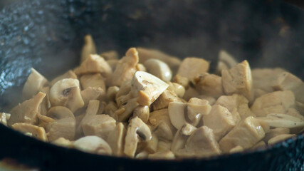 White mushrooms are fried in a pan. Chopped champignons in a pan.