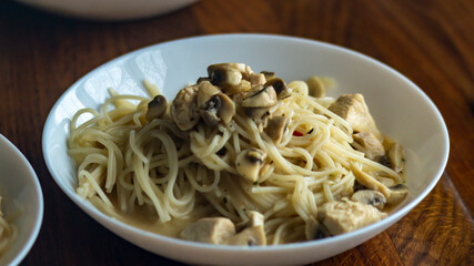 Spaghetti on a plate. Cooked spaghetti on a plate with mushrooms. White plate on a wooden table