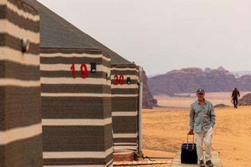 Wadi Rum, Jordan,  A man walks with bag in a boardwalk to check into a desert camp.