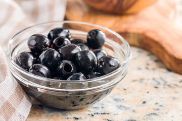 Pitted black olives in bowl on kitchen table.