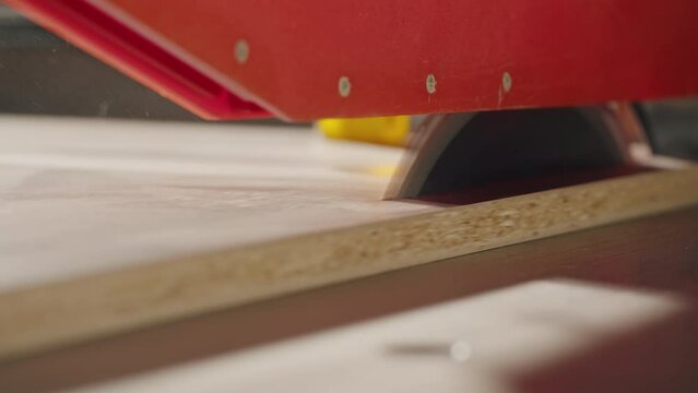 Close-up of carpenter cutting a wooden plank, circular saw on wooden factory, furniture production, handmade craft table.