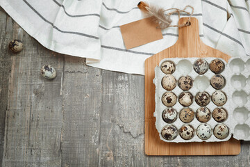 A background with cardboard packaging of quail eggs, board and cloth on the table. The concept of healthy natural organic nutrition with label mock up. Top view. Copy space.