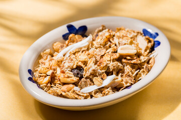 plate with healthy granola on yellow background, top view