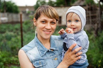 Pretty woman holding a newborn baby in her arms. Laughing baby playing with mother. Portrait of a young mother taking care of her cute baby. Mother smile to her child. Happy mother with son