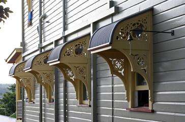 Four windows with vintage carved window awnings on the Queenslander's wall, Brisbane, Australia