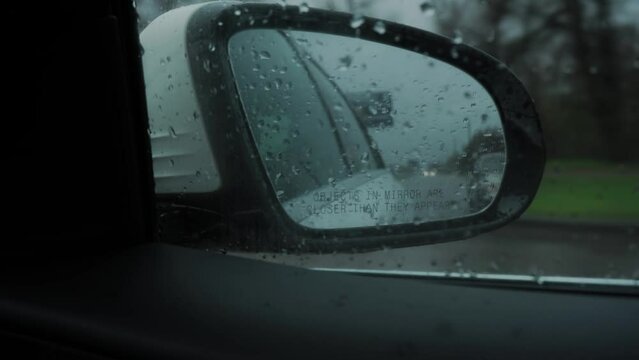 Close-up. Blind Spot Monitor Lights up on the side mirror of the car when overtaking, while driving on the road in the rain