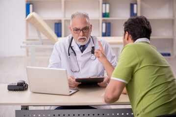 Obraz premium Young male patient visiting old male doctor