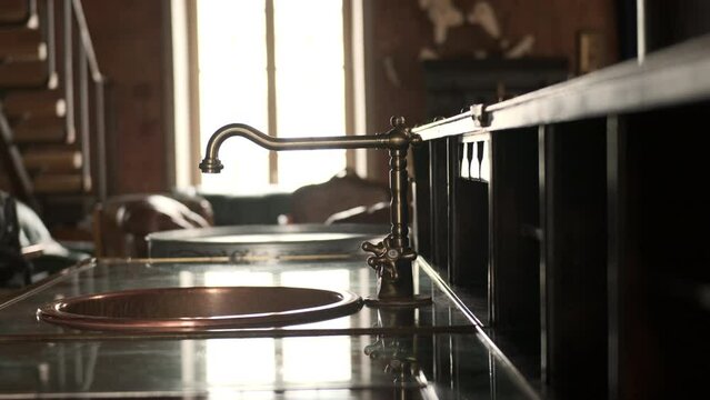 Old vintage copper faucet in kitchen in vintage interior. Retro kitchen faucet with window in background.