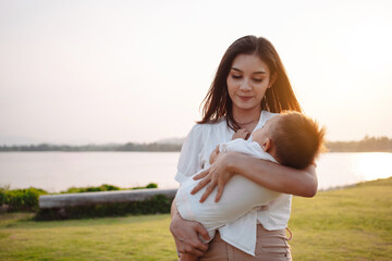 Mother Parenting and newborn birth life. Mom and baby boy playing in park sunset, Family having fun...