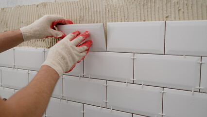 Tile apron in the kitchen. White tiles, leveling clips, tile cement. Laying backsplash tiles in the kitchen. - obrazy, fototapety, plakaty
