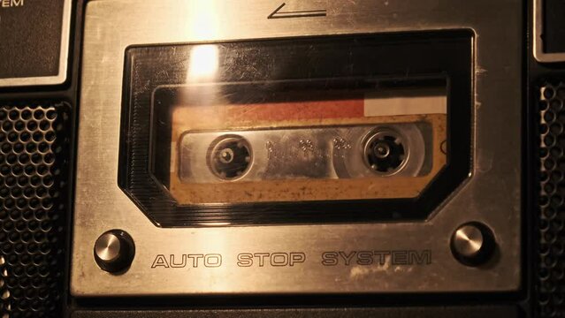 Audio cassette playback in a vintage tape recorder. Record player playing old yellow audio cassette in flickering candlelight, close-up. Retro tape reels rotate in deck. Recording calls, archive, 80s