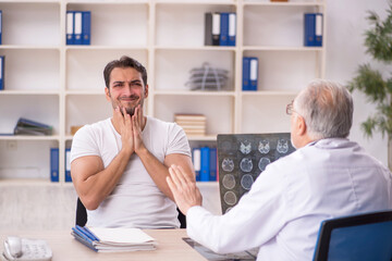 Obraz premium Young male patient visiting old male doctor radiologist