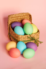 Colored Easter eggs in a square basket on a pink background. Easter