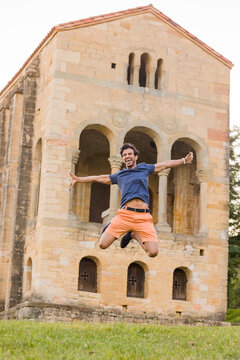 Inspirational fun jump movement. South asian mid adult man triumphing on travel vacations in Asturias