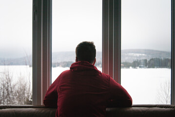 Sad man looking out the window during a foggy winter day